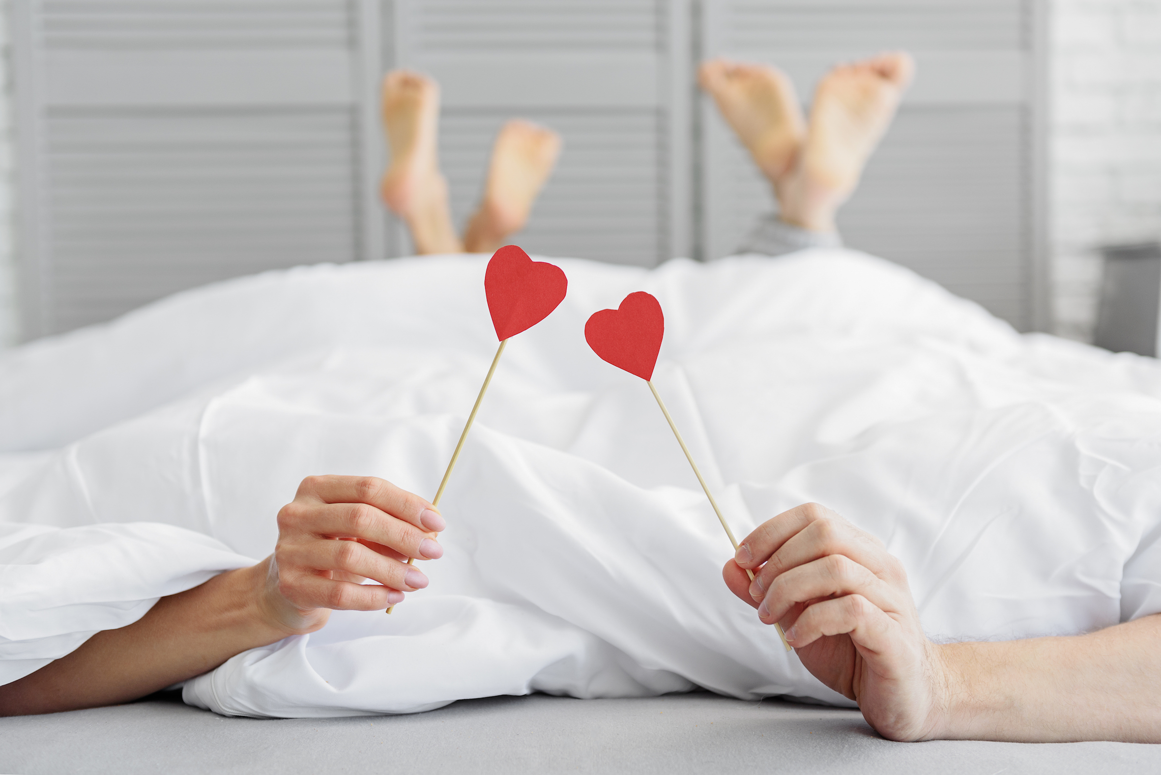 couple holding hearts in bed