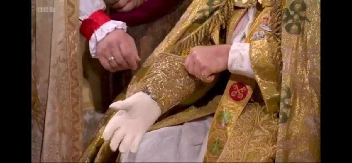 Charles III pulling on his grandfather's glove during his coronation on May 6. Photo credit: Alibaba Group